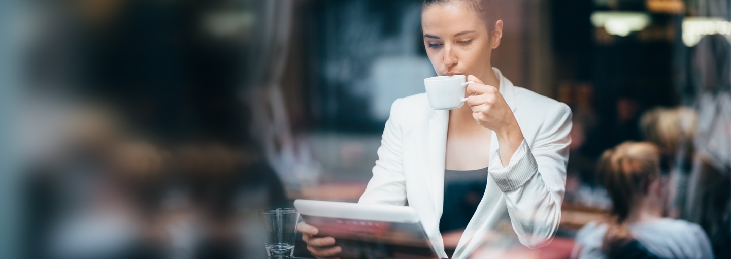 kobieta w kawiarni czytająca newsy na tablecie